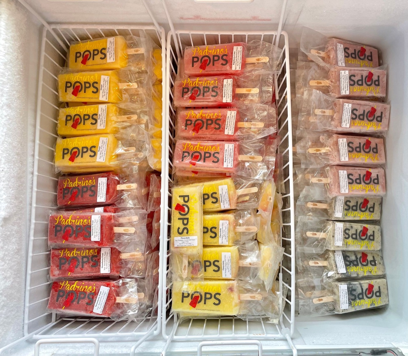 Wrapped Padrino's Pops paletas standing in rows in a freezer